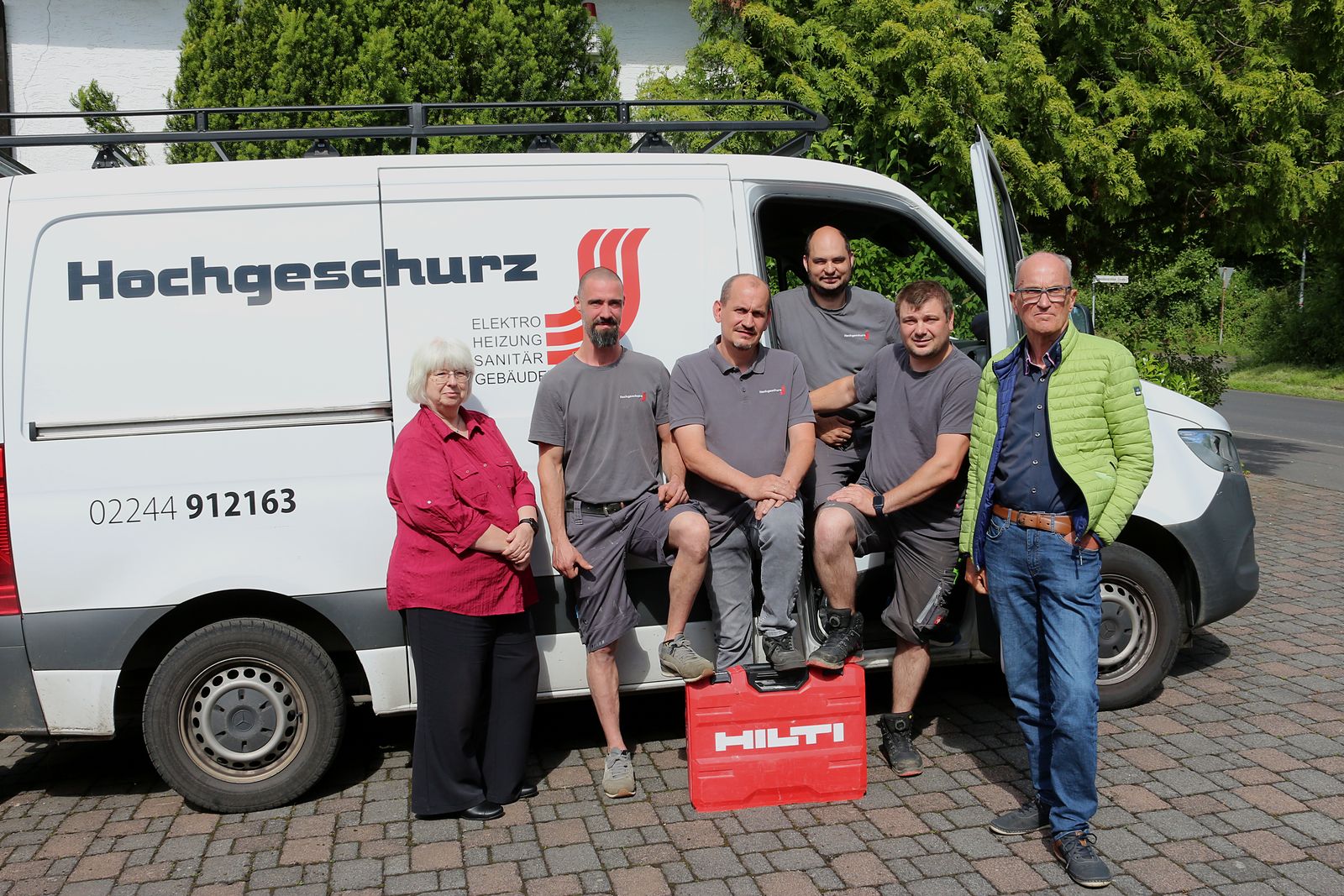 Familie Hochgeschurz mit dem Team: Seniorchefs, Firmeninhaber und Monteure am Firmenfahrzeug